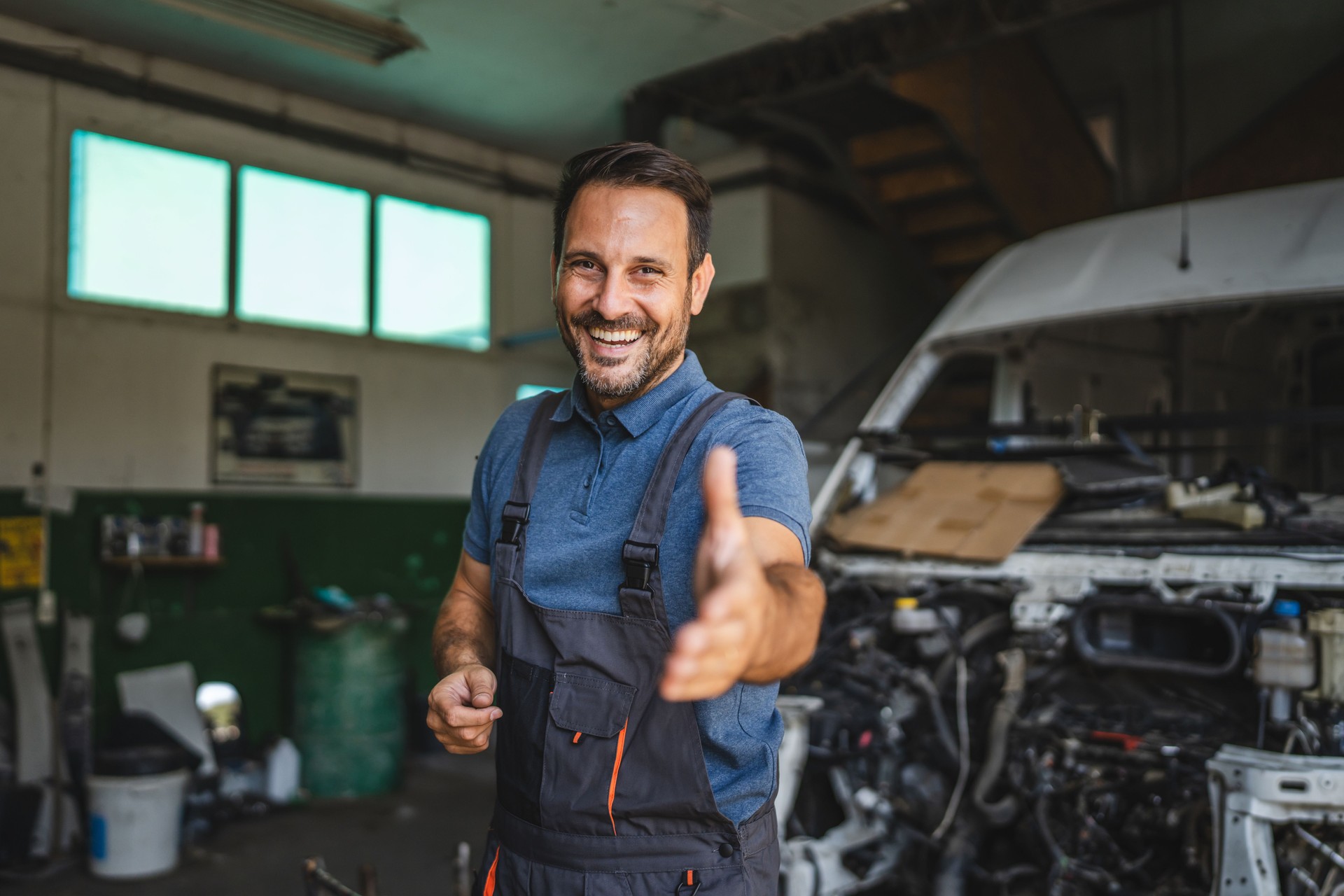Friendly mechanic reaching out with a smile in auto repair shop